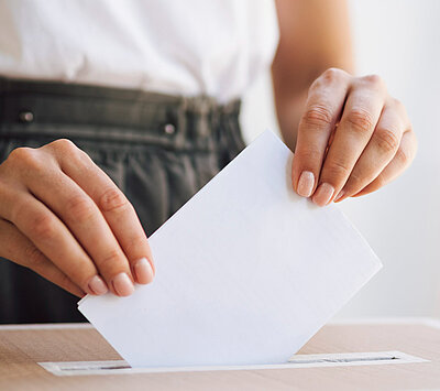 A person putting a ballot paper into a ballot box